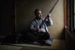 Endo-san sostenint un rifle que havien fet servir els seus ancestres i, al seu costat, una pell d’os negre japonès que decora l’habitació / Javier Corso / OAKstories 